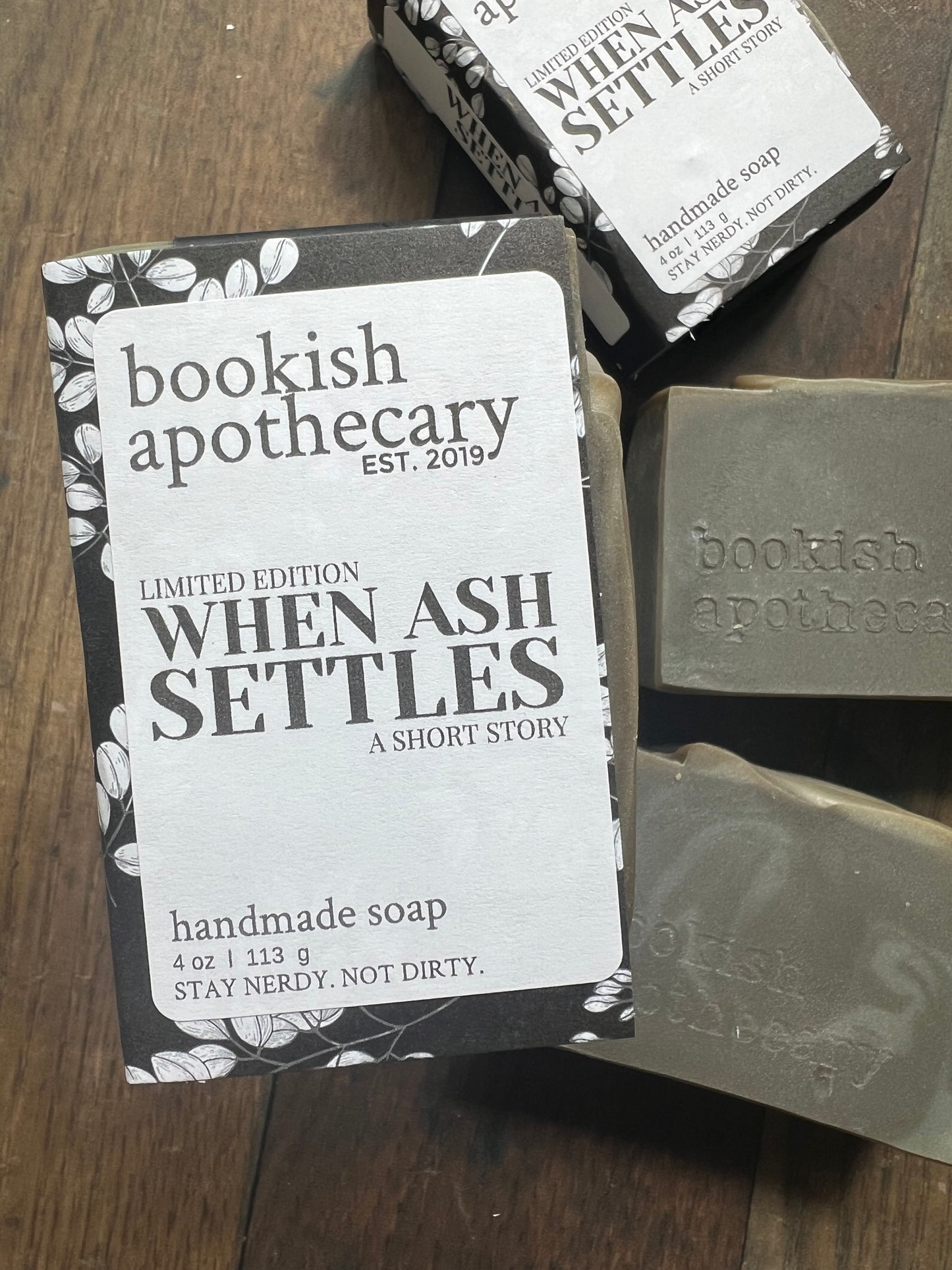 Handmade soap bars with 'bookish apothecary' branding on a wooden surface