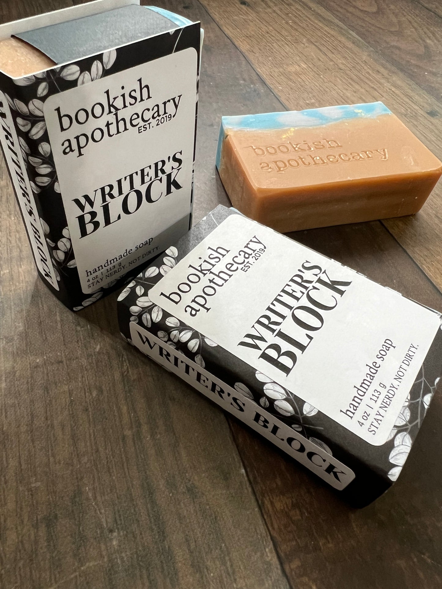 Two bars of soap with 'Bookish Apothecary' packaging on a wooden surface.