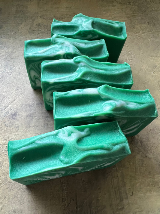 Five green marbled soap bars arranged on a textured gray surface.