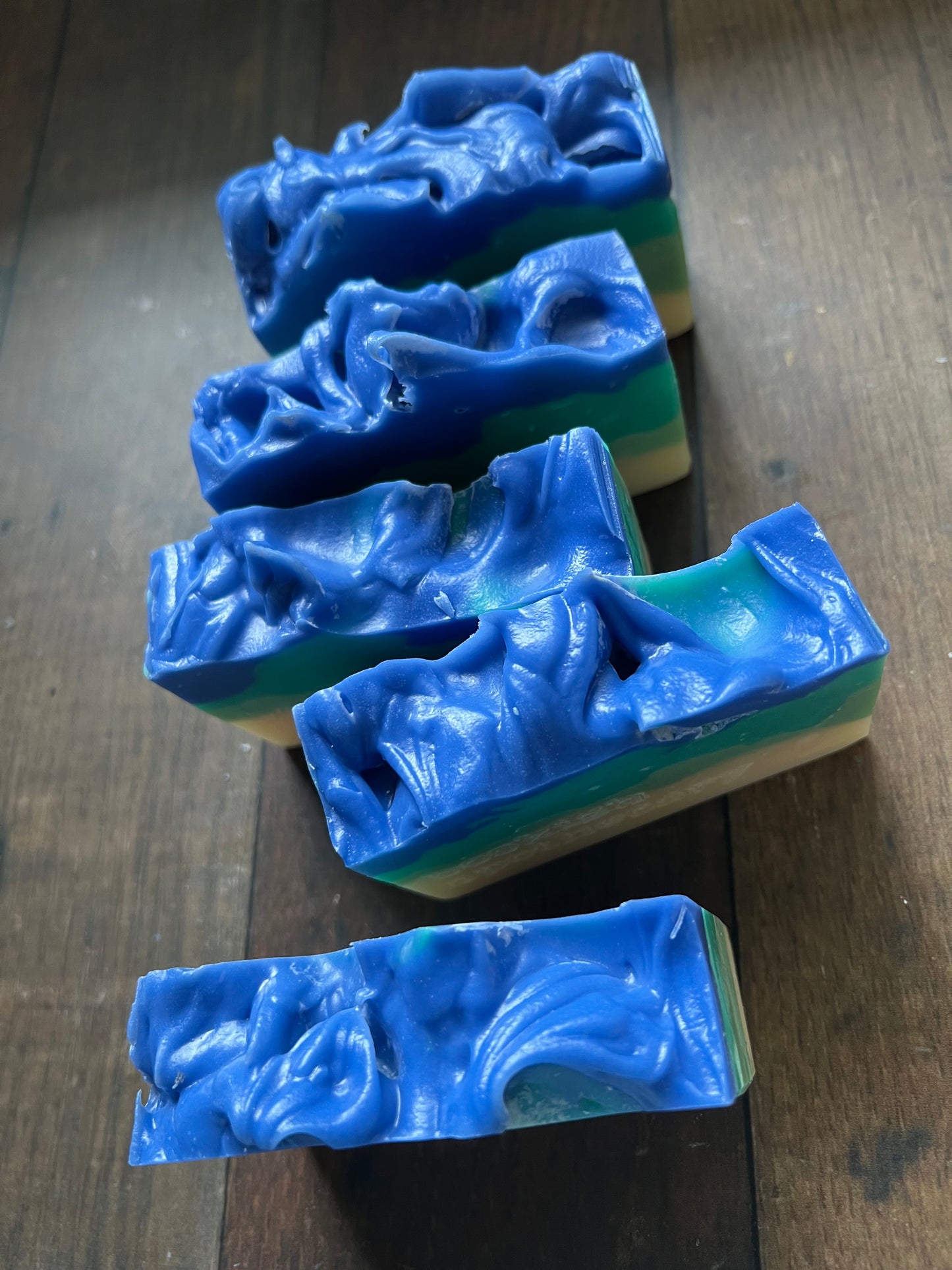 five blue soap bars with a wavy pattern on a wooden surface
