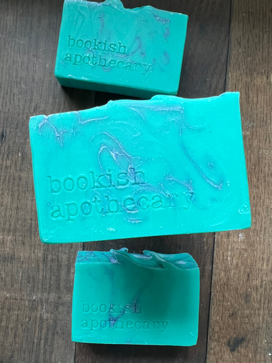 Three pieces of green soap with 'bookish apothecary' branding on a wooden surface.