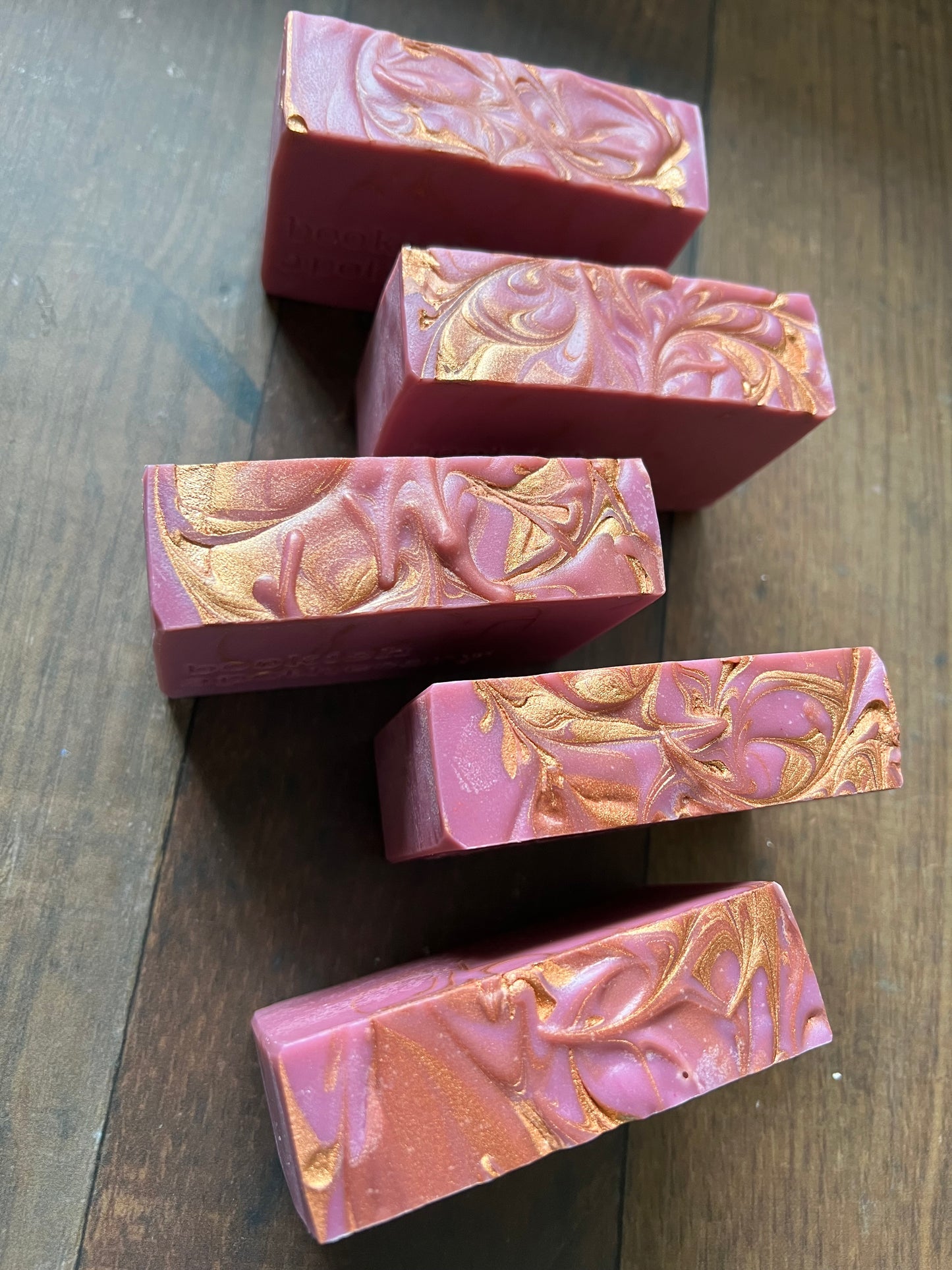 Pink and gold marbled soap bars on a wooden surface