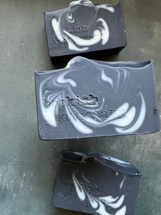 Three bars of black and white marbled soap on a gray surface