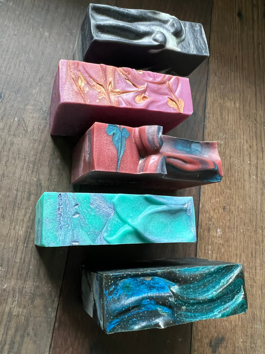 Five colorful soap bars with marbled patterns on a wooden surface