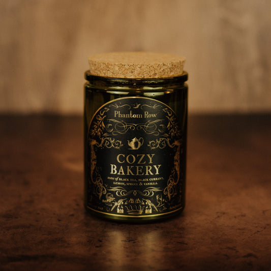 Jar of 'Cozy Bakery' candle by Phantom Row on a wooden surface with a warm background