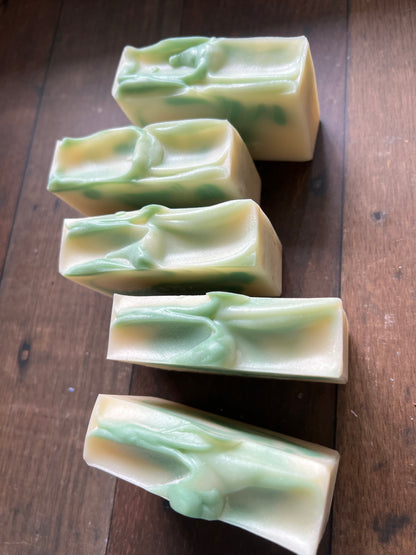 Five bars of white and green soap on a wooden surface
