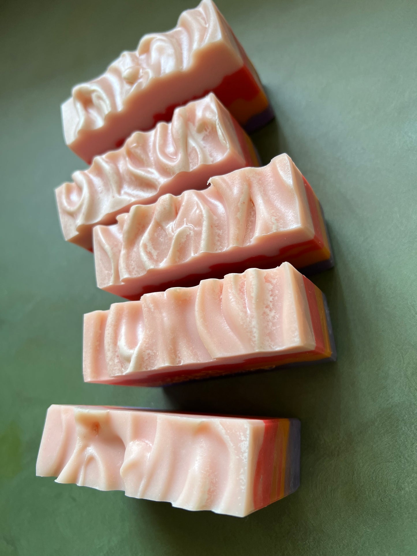 five bars of soap with layers of pink, red, orange and purple stamped with bookish apothecary branding.