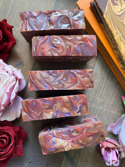 Swirl-patterned soap bars on a wooden surface with flowers around