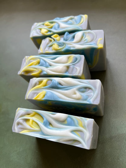 five bars of gray soap with blue, yellow and white swirls stamped with bookish apothecary branding.