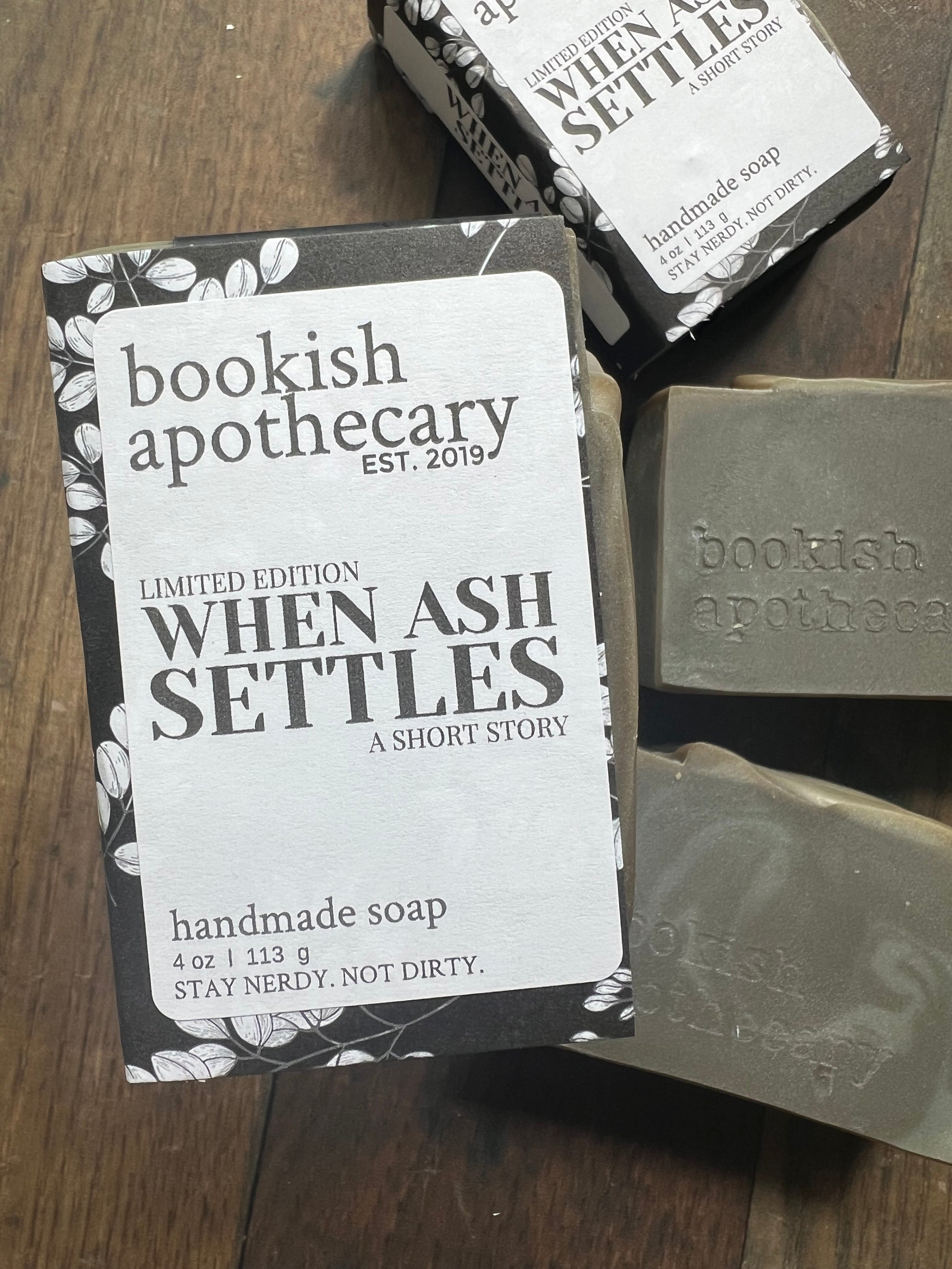Handmade soap bars with 'bookish apothecary' branding on a wooden surface