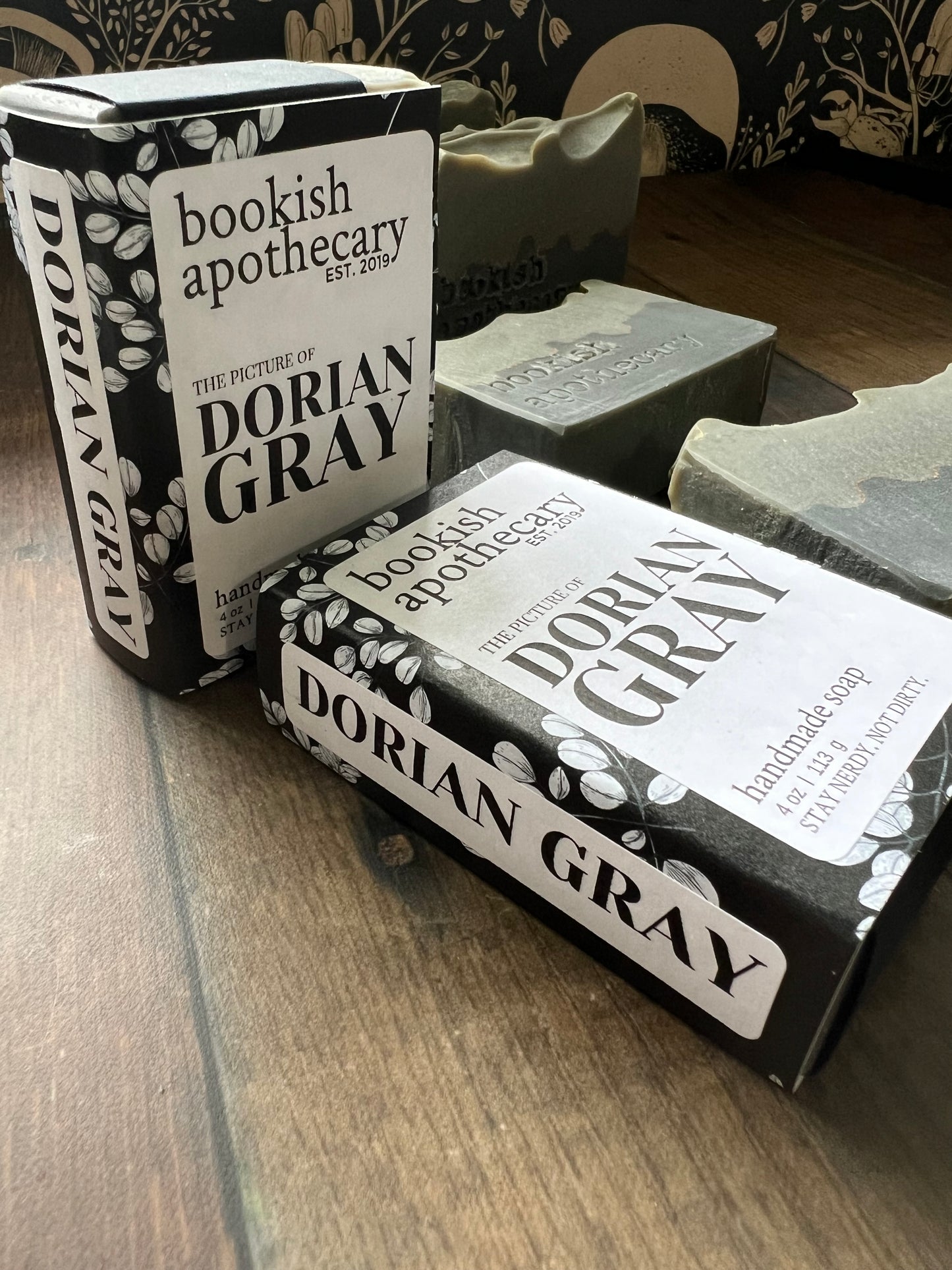 Two bars of packaged soap from 'bookish apothecary' on a wooden surface