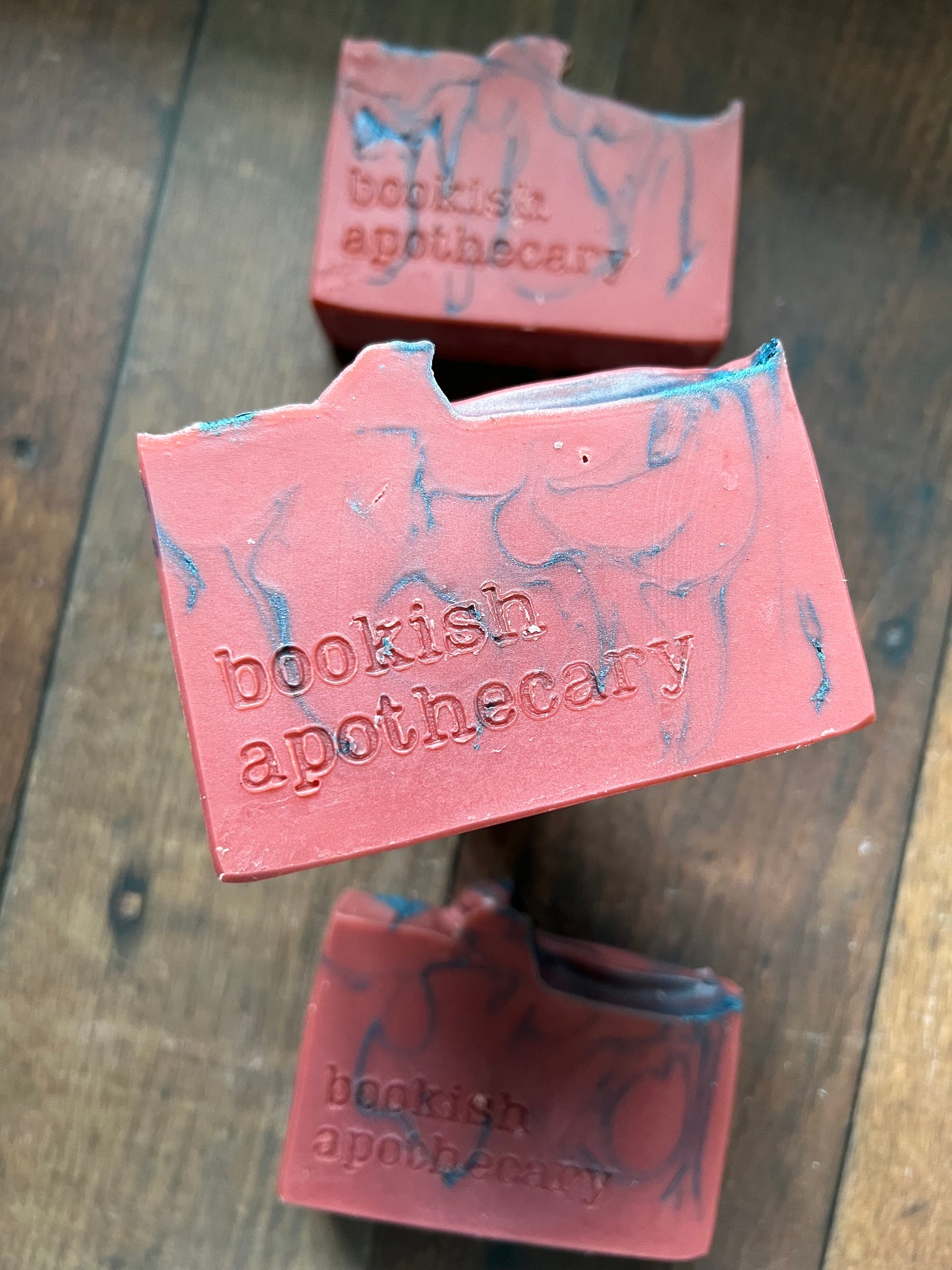 red soap with 'bookish apothecary' branding on a wooden surface