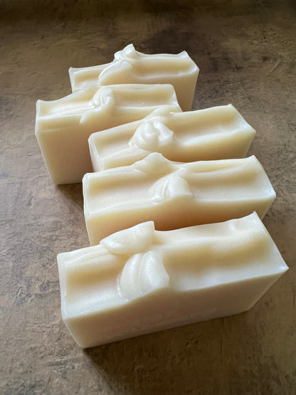 Five rectangular bars of handmade soap with textured tops , arranged diagonally on a textured brown surface.
