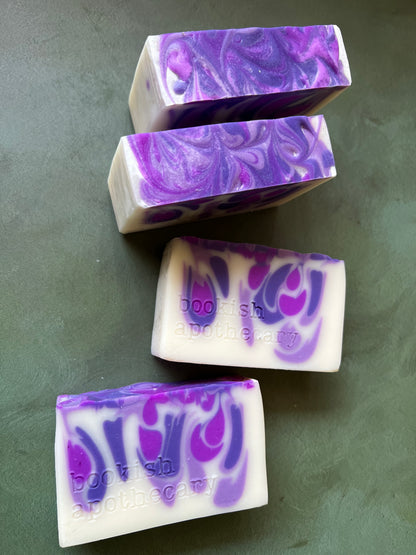 four bars of white soap with purple swirls stamped with bookish apothecary branding.