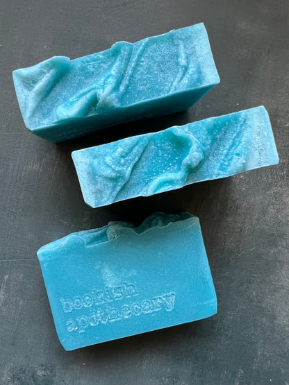 Three bars of blue soap on a dark surface