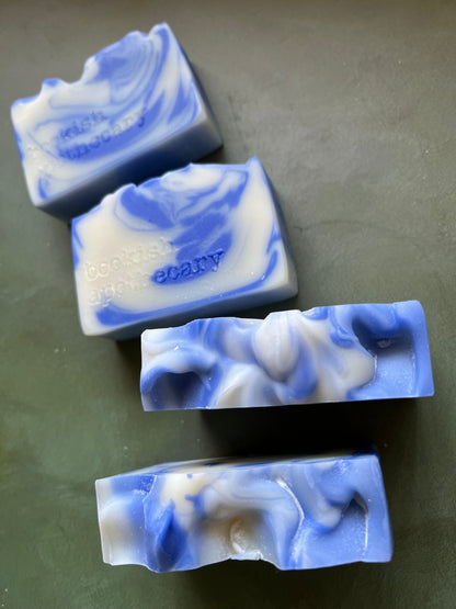 Four bars of blue and white swirled soaps stamped with bookish apothecary branding.