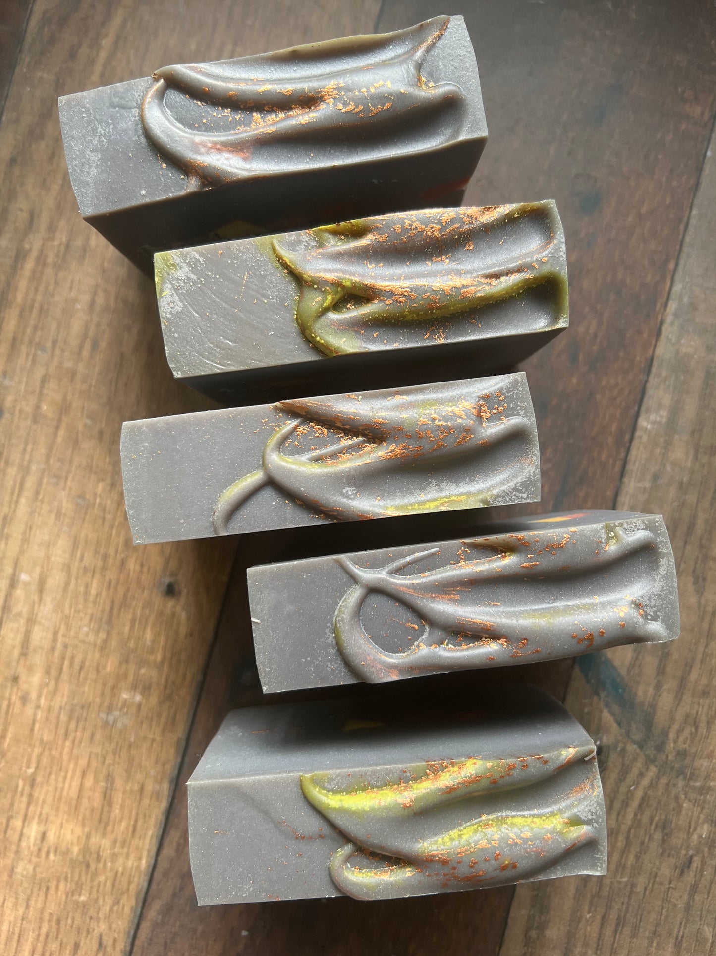 five bars of soap with textured tops on a wooden surfaces