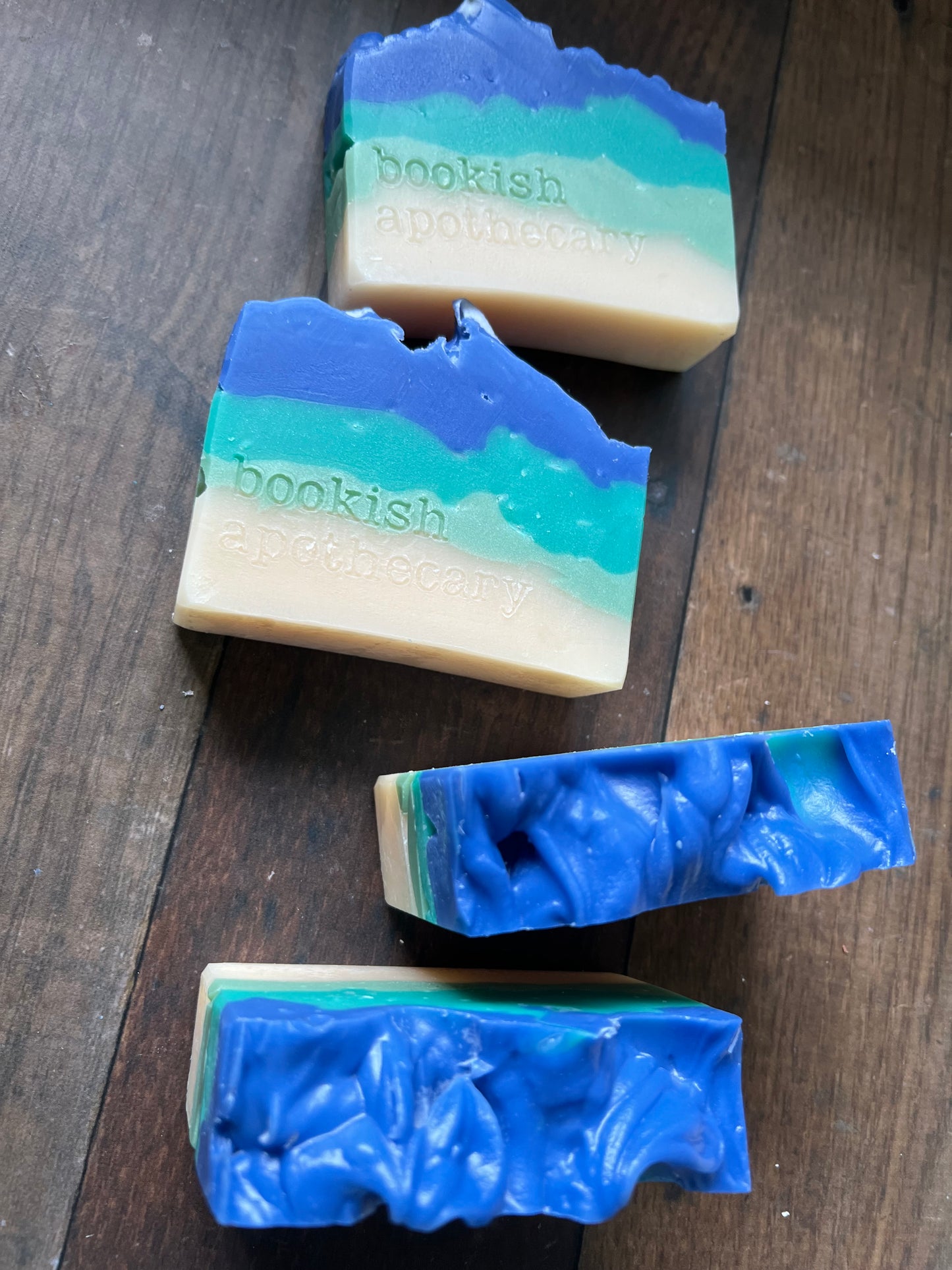 Four bars of soap with blue and green gradient on a wooden surface
