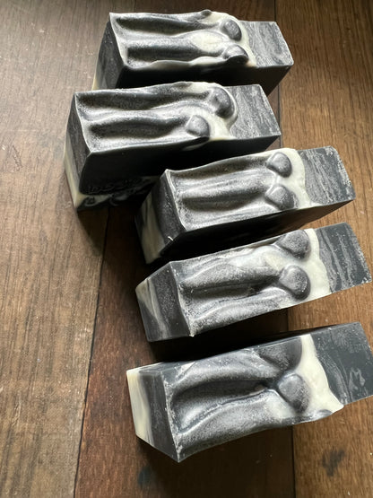 Five bars of black and white soap on a wooden surface