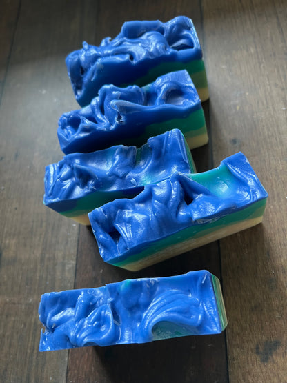 five blue soap bars with a wavy pattern on a wooden surface