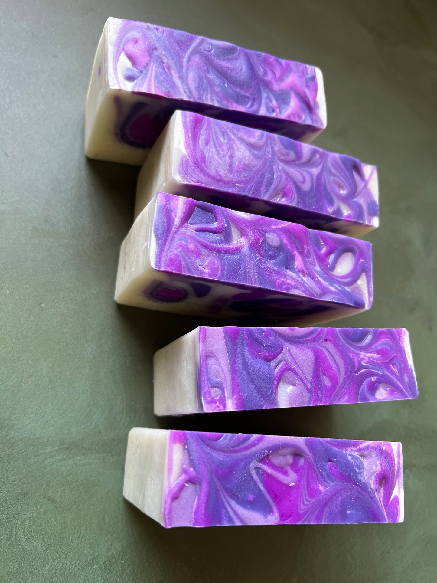 five bars of white soap with purple swirls stamped with bookish apothecary branding.
