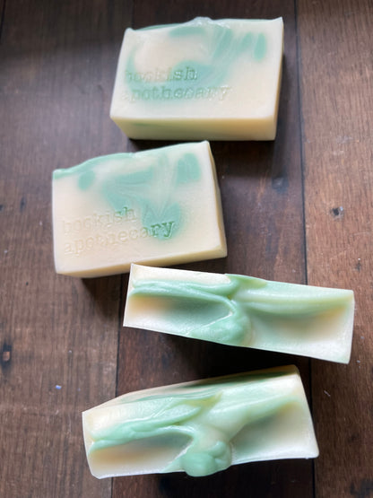 Four green soap bars on a wooden surface