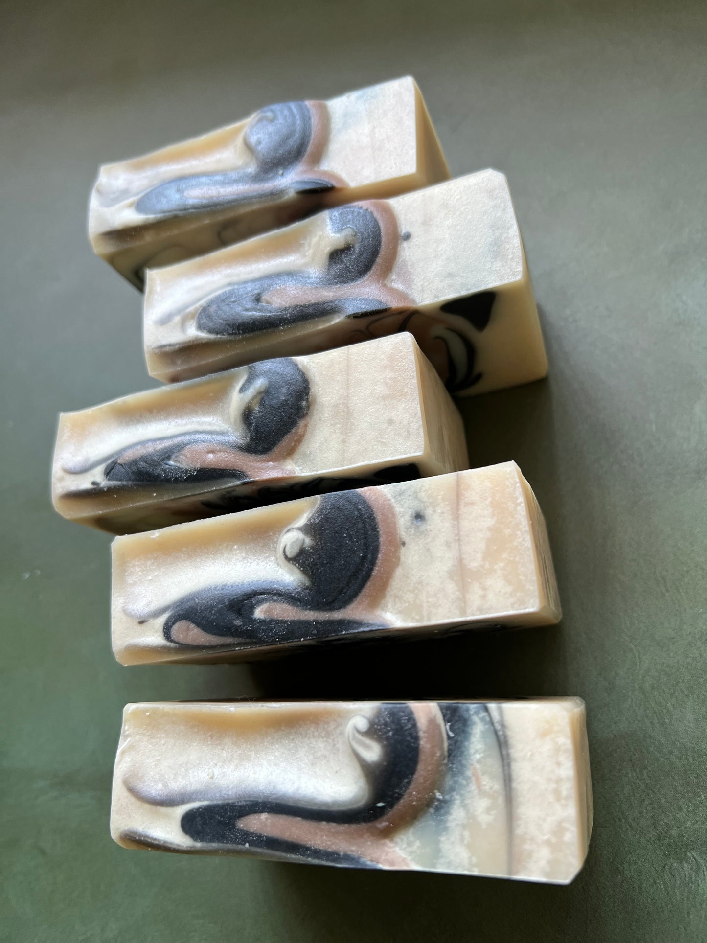 five bars of white soap with black and tan swirls stamped with bookish apothecary branding.