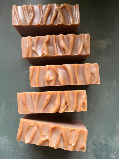 Five bars of soap with wavy patterns on a dark surface