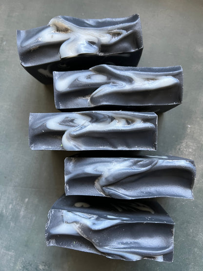 Five bars of black and white marbled soap on a gray surface