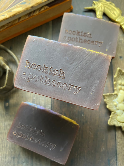 Three bars of soap with 'bookish apothecary' branding on a wooden surface.