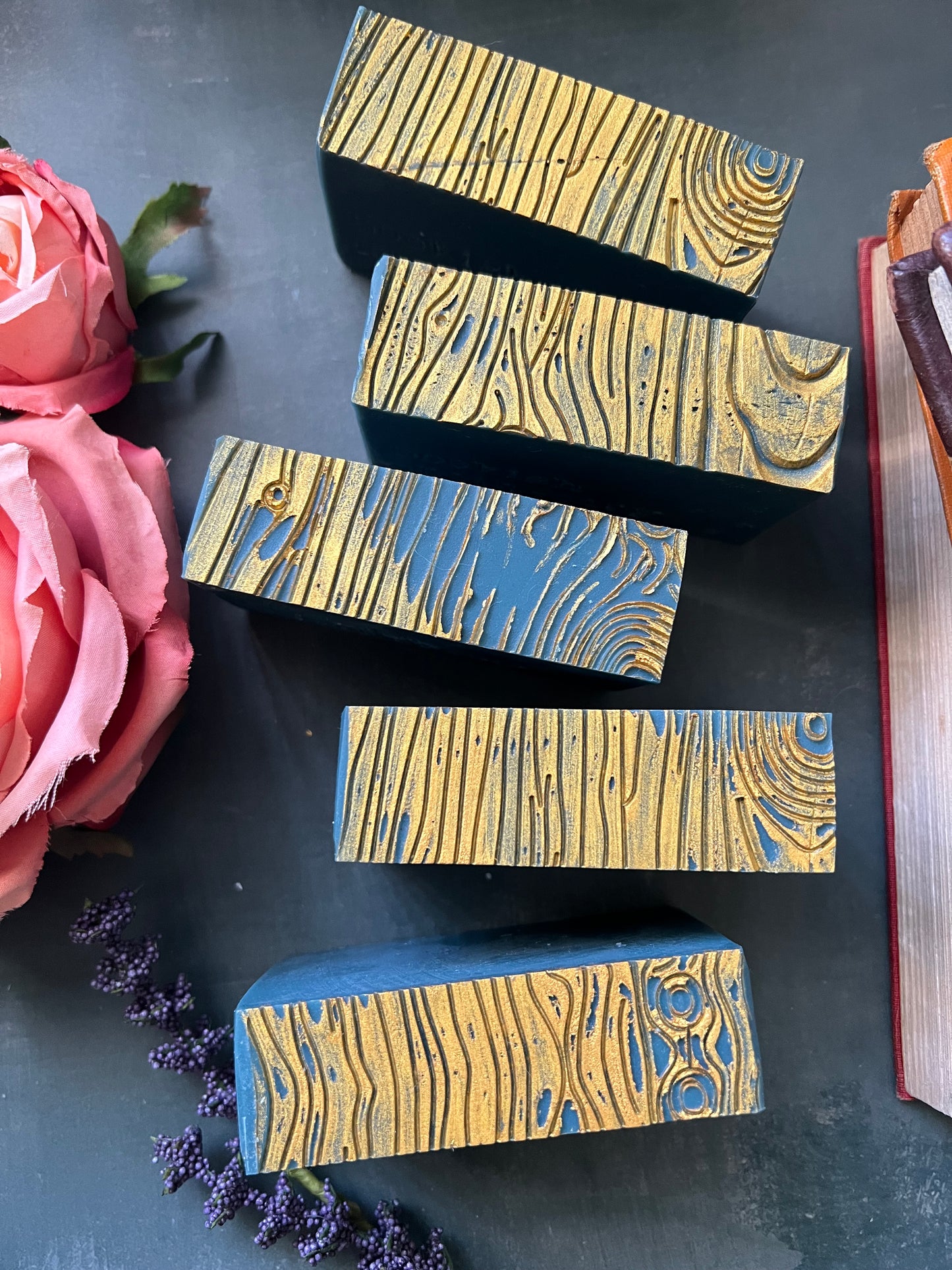 Wooden printing blocks with wavy patterns on a dark surface with flowers.