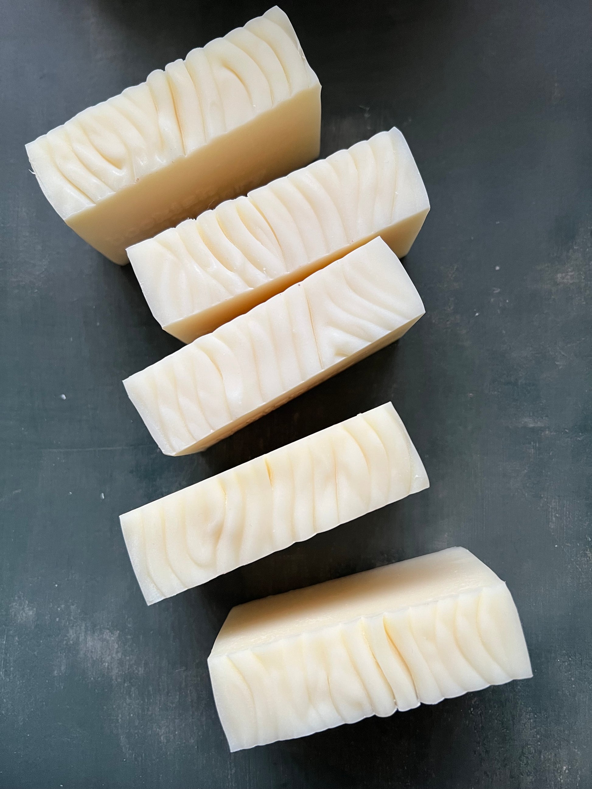 Six rectangular blocks of soap arranged in a row on a dark surface