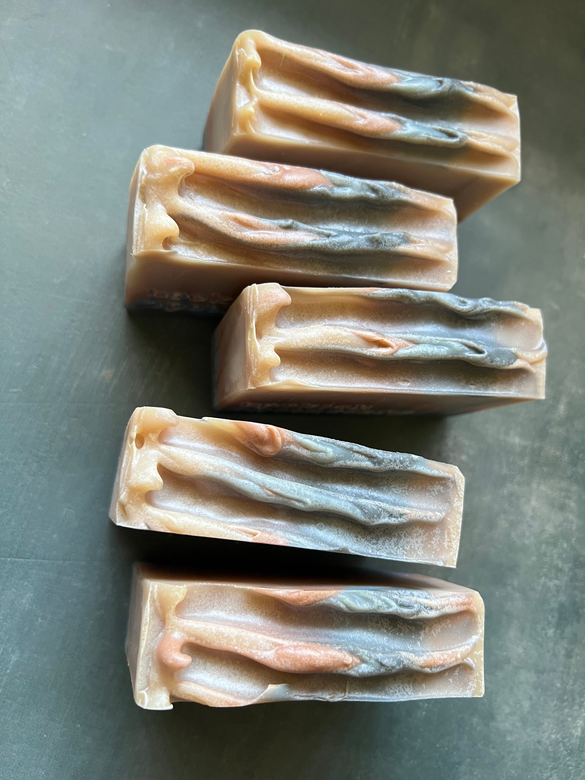 Five rectangular bars of soap with a natural, beige color on a gray surface.