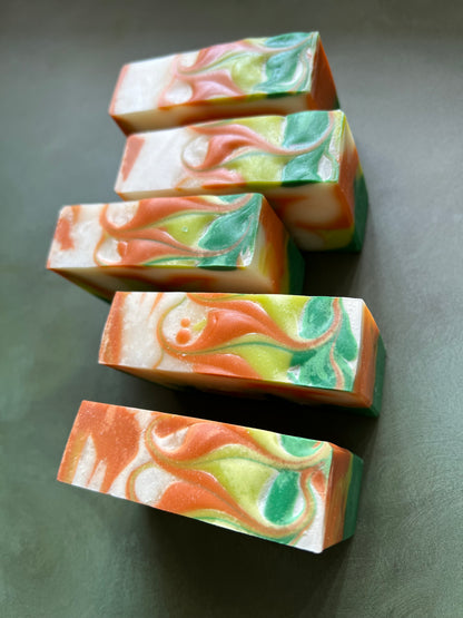 five bars of swirled soaps comprised of orange, chartreuse and green soap stamped with bookish apothecary branding.