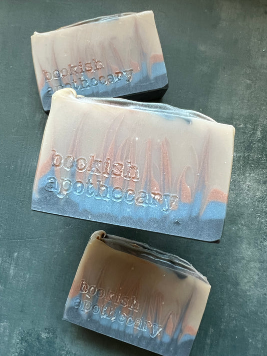 Three bars of soap with 'bookish Apothecary' branding on a gray surface.