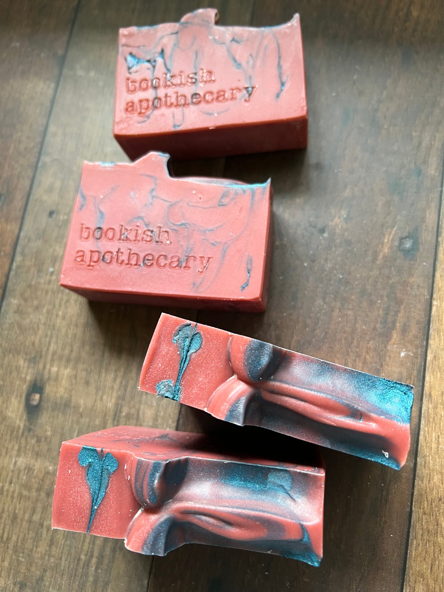 Four bars of soap with 'bookish apothecary' branding on a wooden surface.
