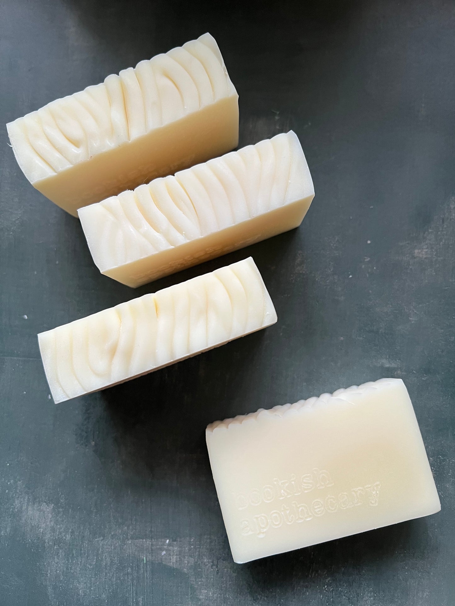 Four rectangular soap bars with textured surfaces on a dark gray background