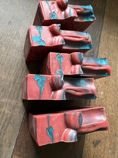 Five red and blue marbled soap bars on a wooden surface