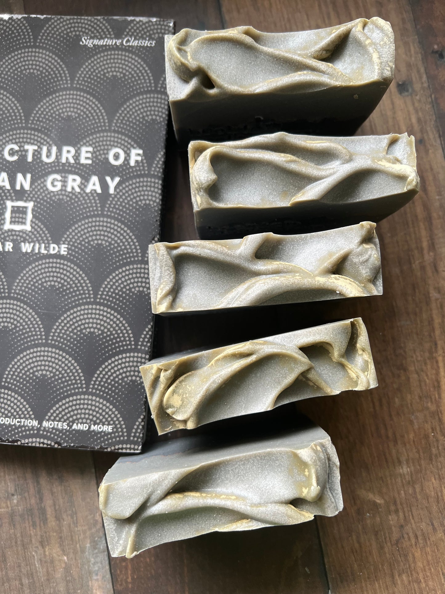 Five bars of soap with textured tops from 'bookish apothecary' on a wooden surface