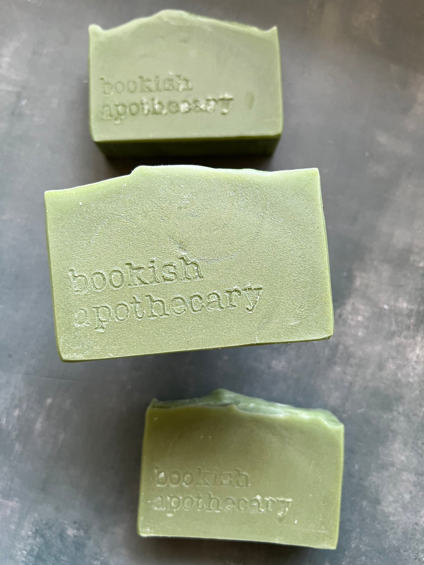 Three green bars of soap from Bookish Apothecary on a gray surface