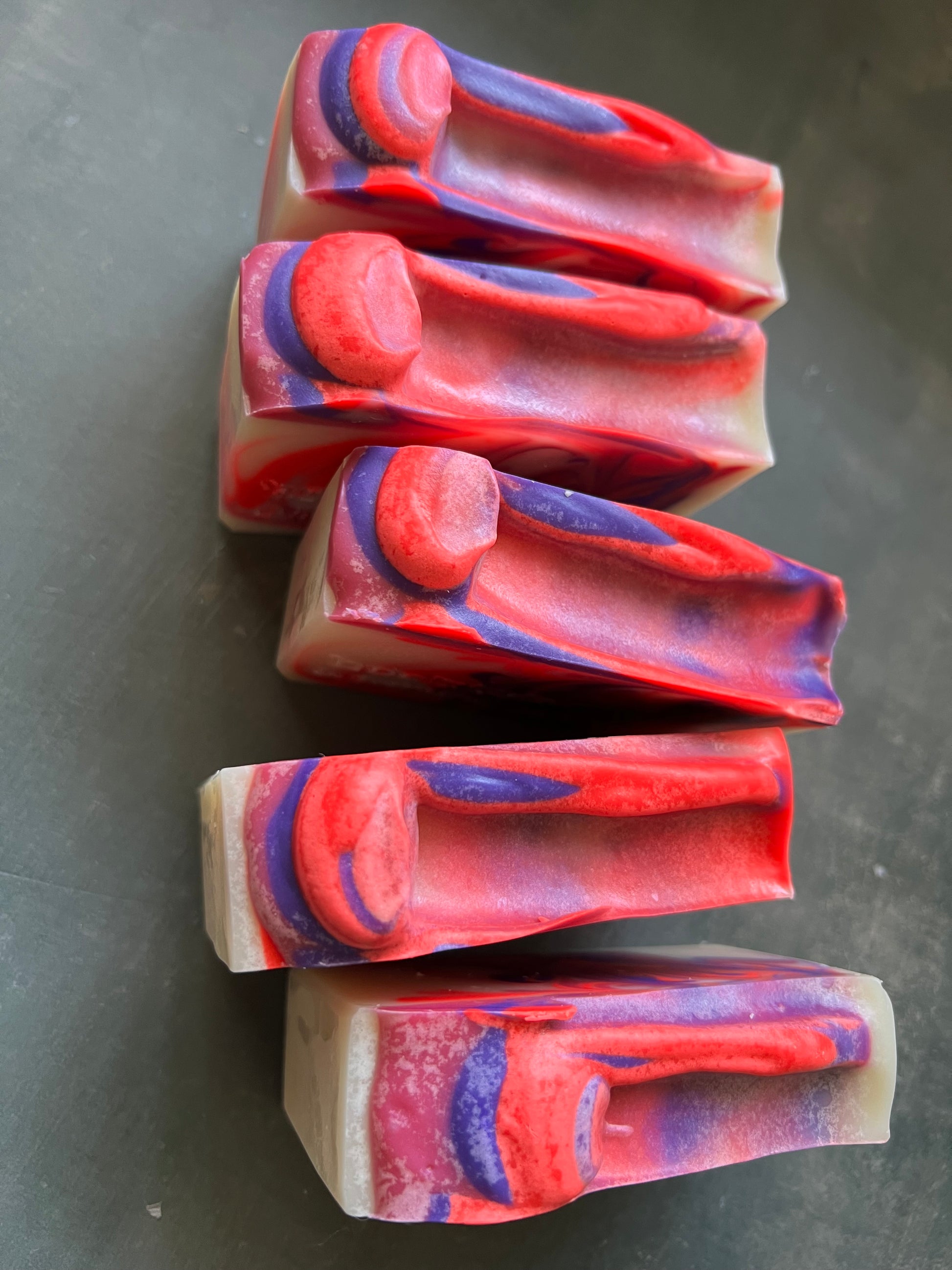 Colorful soap bars with a marbled pattern on a dark surface