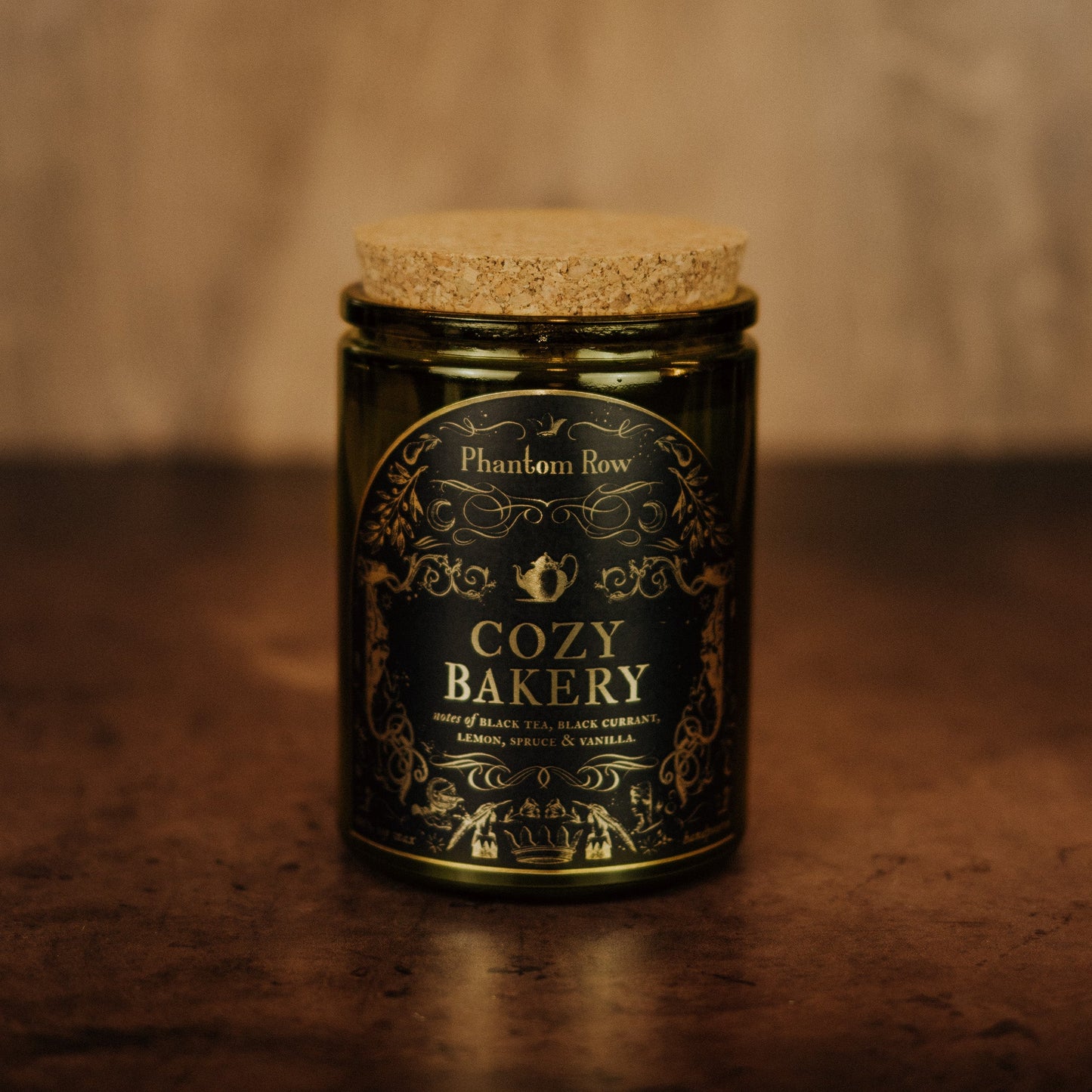 Jar of 'Cozy Bakery' candle by Phantom Row on a wooden surface with a warm background