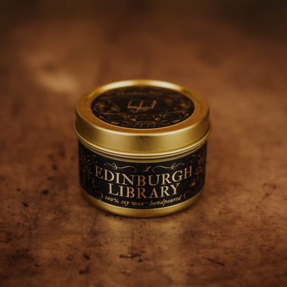 Candle in a tin labeled 'Edinburgh Library' on a textured brown background