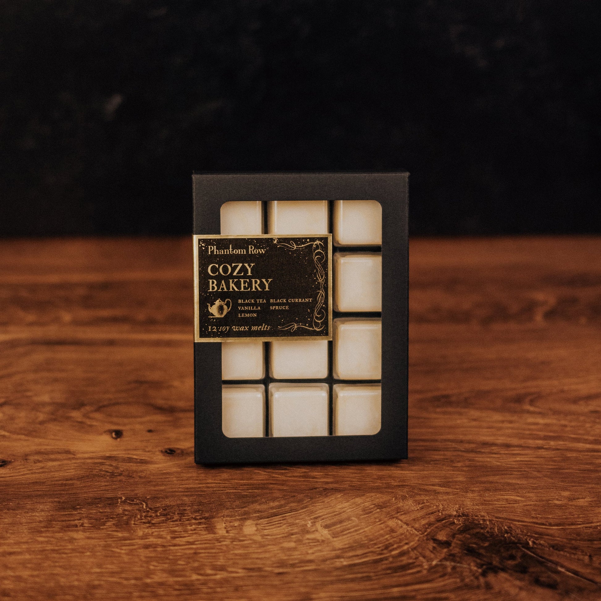 Box of 'Cozy Bakery' wax melts on a wooden surface with a dark background