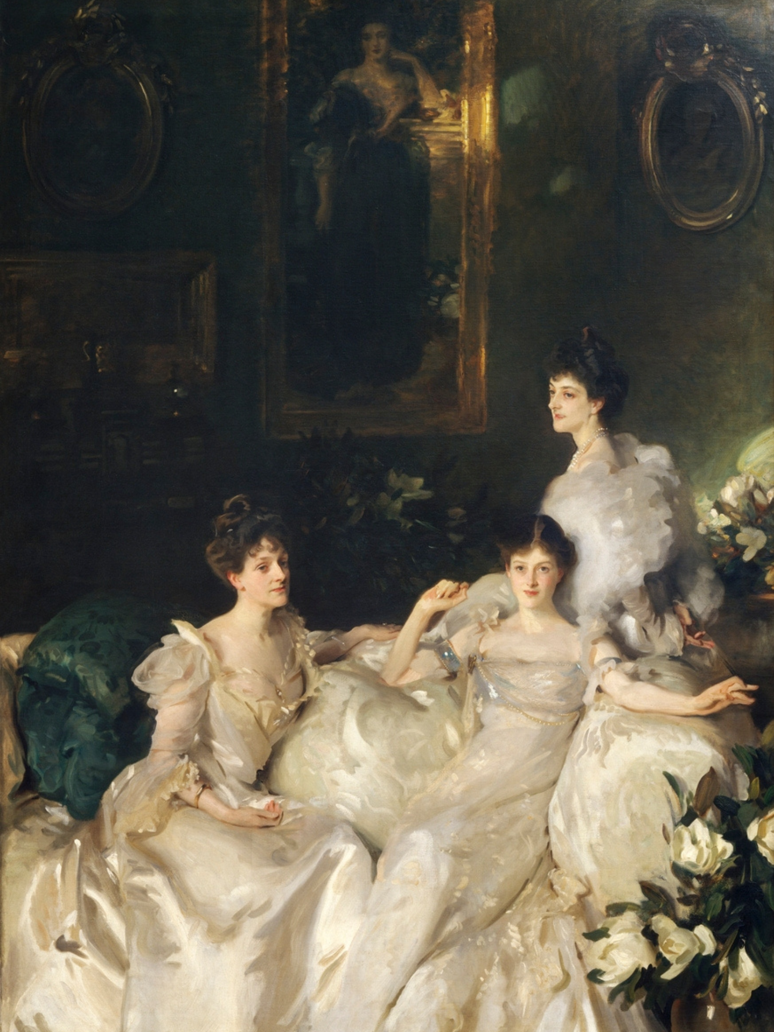 Three women in formal attire sitting together with decorative elements in the background