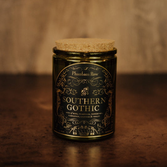 Candle jar labeled 'Southern Gothic' by Phantom Row on a textured surface with a blurred background